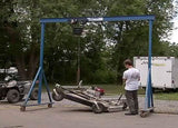 Gorbel blue adjustable gantry crane 2 ton lifting a tool with a person standing nearby outdoors