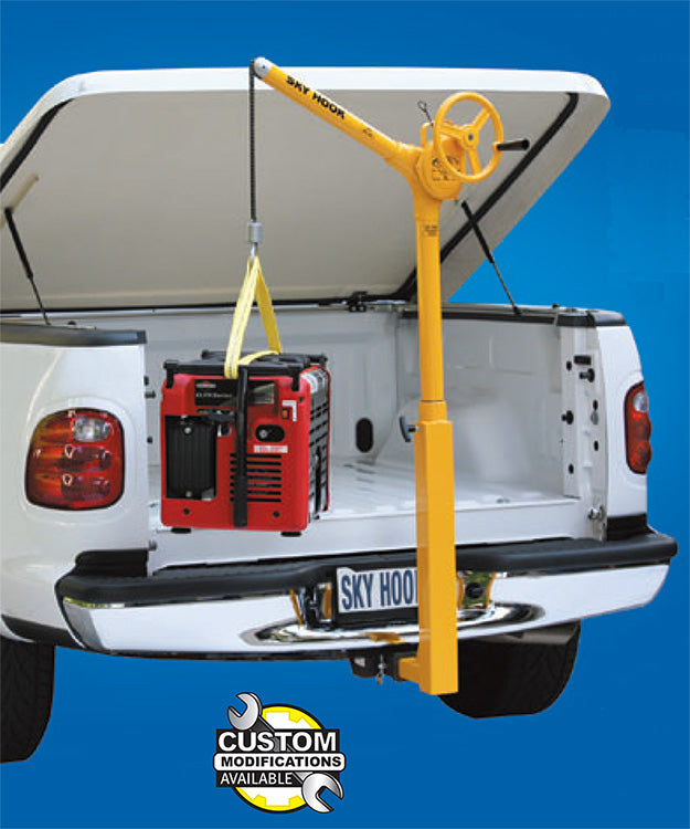 Yellow truck mounted lifting device from Syclone Attco Service lifting a red generator in a white pickup truck bed